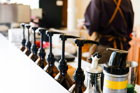 Row of pump head bottle of beverage in the cafe,Pump at the head of bottles for caramel, syrup and smell addition for coffee in cafe,Space for text,closeup concept.