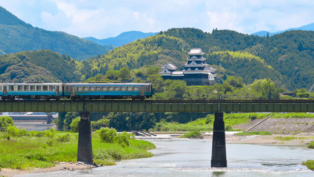 A limited express train on the Tokushima Line crossing the iron bridge over the Anabuki River in Ozu, Japan, Aug 2023
