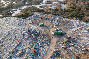 Aerial view of garbage pile in trash dump with dump track unload garbage at landfill. Biohazard for ecosystem and healthy environment concept. Environmental pollution and ecological disaster - 762483992