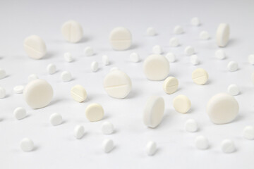 Lot of white round pills on the bright surface. Different tipes of drugs