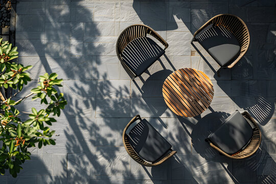 A top view of a set of garden chairs and a table casting symmetrical shadows on a patio, showcasing a summer outdoor living space
