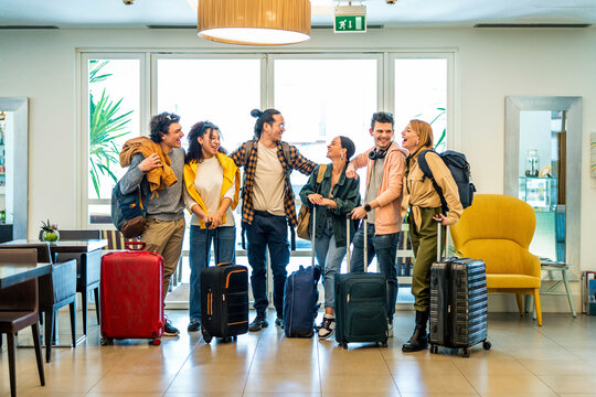 Young group of tourists with suitcases arriving at youth hostel guest house - Happy friends enjoying summer vacation together - Millenial people doing check-in at hotel lobby - Summertime holidays