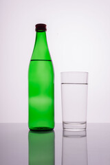 green mineral water bottle with glass on white background