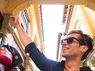 Smiling handsome man with sunglasses and black shirt at handicraft market in Granada Spain pointing up left - 762498563
