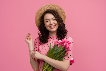 pretty young woman posing isolated on pink studio background with tulips flowers