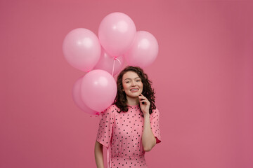 pretty young woman posing isolated on pink studio background with pink air balloons