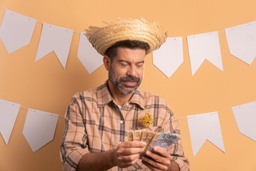 cheerful bearded man to Brazilian Junina Festival in beige colors. with brazil banknotes currency 
