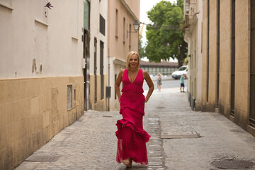Mature woman, beautiful, blonde, with a pink flamenco suit with ruffles and polka dots, happy and...