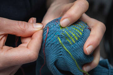 Mending clothes. Visible mending repairing sock. Darning old socks, reducing waste, slow fashion. Repair concept, selective focus. - obrazy, fototapety, plakaty
