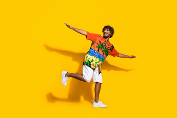 Fototapeta na wymiar Full size photo of positive man dressed print shirt hold palms like wings look at promo empty space isolated on yellow color background