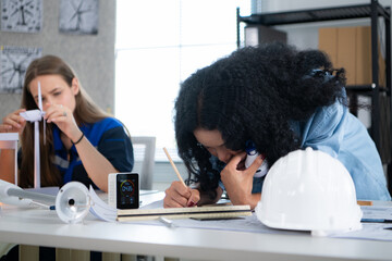 Young female architect working on blueprint with colleague in office