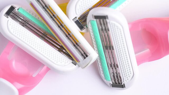 Close up of pink and yellow disposable razors on white table. Macro shoot of the razor blade, rotation.