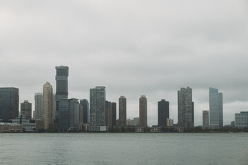 Fototapeta na wymiar Cloudy Skyline View of New York City's Waterfront Architecture