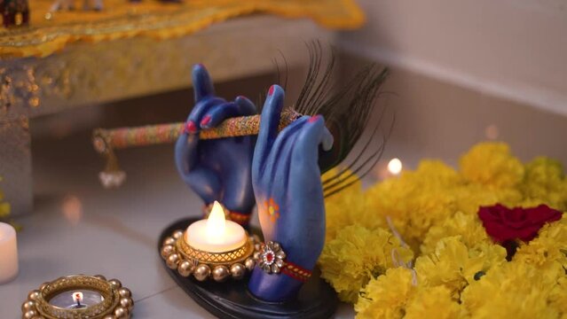 Lord Krishna Flute in Hand Figurine for Festival Decoration with Marigold flowers and Diya in Background | Indian Religious Background