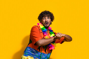 Photo of impressed man with afro hairstyle dressed print shirt flower necklace dancing staring at sale isolated on yellow color background
