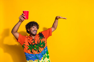 Portrait of positive guy with afro hair wear shirt hold cup of beer look at event promo empty space...