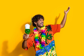Photo of ecstatic man wear print shirt hold exotic drink raising arm up look empty space isolated...