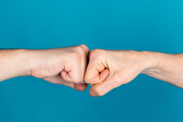 Photo of two mature young people arms palms hands touching fists having confrontation isolated blue color background