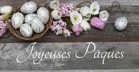 Carte de voeux Joyeuses Pâques. Décoration avec des fleurs, des œufs de Pâques et l'inscription...