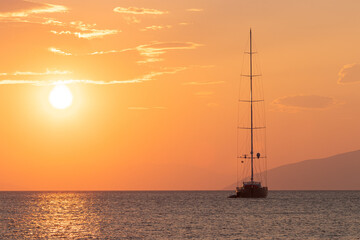 Luxury catamaran sailing vessel with dramatic sky at sunrise.	