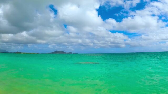 Seascape near Lanikai Beach, Hawaii. Peaceful ocean bay with clear aquamarine water, cloudy sky and faraway mountains. Sunny summer day at the beach.