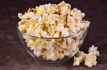 Popcorn in a glass transparent bowl on a dark background.Close-up.

