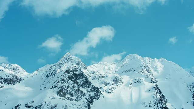 Timelapse of clouds flying over Austrian Alps mountains. Beautiful cold sunny winter day with snowy mountain peaks