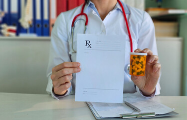 Doctor holding form with prescription and blister of medicines in clinic closeup