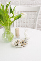 Beautiful table serving for Easter celebration in dining room, plates with easter eggs and bunny, vase with flowers. Easter table setting.