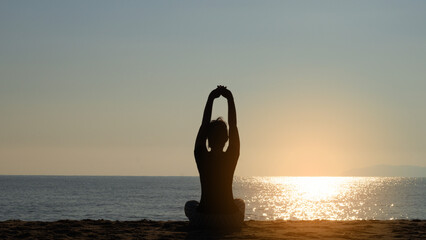 Silhouette yoga, Asia young woman practicing yoga on the beach. sunrise in the morning at the beach.