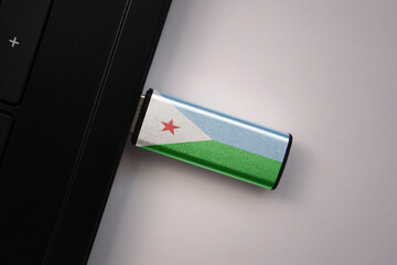 usb flash drive in notebook computer with the national flag of djibouti on gray background.