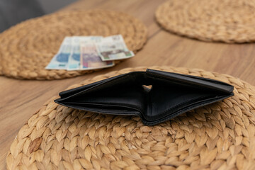 Pusty portfel obok ostatnich banknotów to metafora trudności związanych z wydatkami w budżecie...