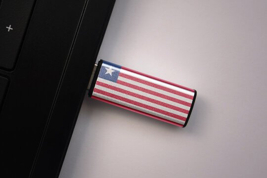 usb flash drive in notebook computer with the national flag of liberia on gray background.
