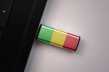 usb flash drive in notebook computer with the national flag of mali on gray background.