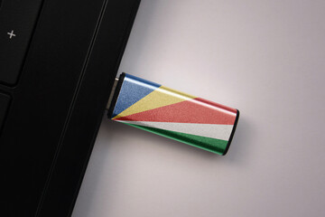 usb flash drive in notebook computer with the national flag of seychelles on gray background.