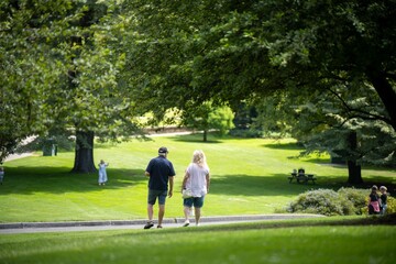 happy married couple walking in a green garden park exploring nature in a city