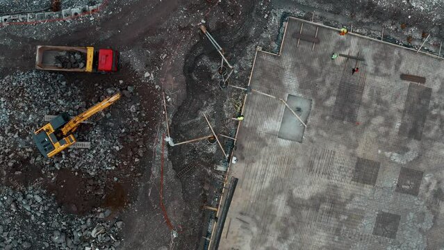 Aerial top view of construction site with excavators and dump trucks during earthworks and building foundation construction. Construction industry