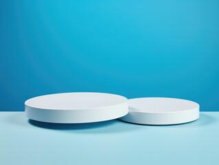 Two white round pedestals are placed on blue background. Pedestals are empty and appear to be made of plastic. Blue background gives scene calm and serene mood
