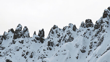 Mountain silhouette and close up structure of Dolomites rocks after heavy snowfall with blue sky. 
