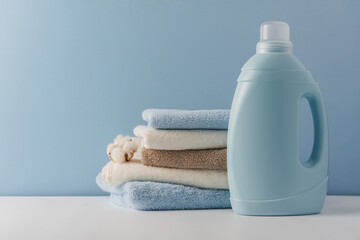 Blue container for liquid laundry detergent against the background of a stack of clean cotton towels