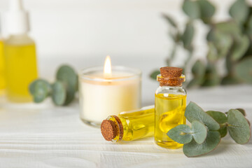 Obraz na płótnie Canvas Eucalyptus essential oil in a glass bottle with green eucalyptus leaves on a textured wooden background. Aromatherapy concept. Spa. Natural organic ingredients for cosmetics and body care.Copy space