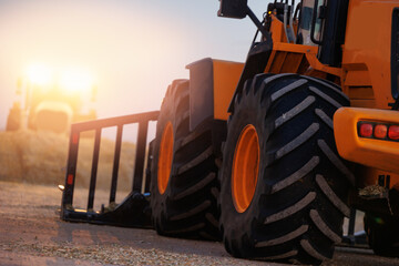 Tractor with pitchfork working with unloading silage at dairy farm, fresh harvest chopped maize...