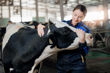 Gordijnen Farmer Happy young woman hugging cow with sun light, concept veterinary health care © Parilov