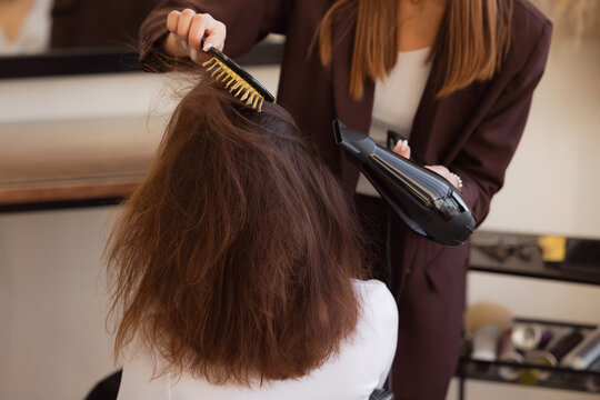 Woman hairdresser use hair dryer and brush for client model in barber salon for girl, female stylist