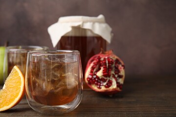 Tasty kombucha with ice cubes and fruits on wooden table