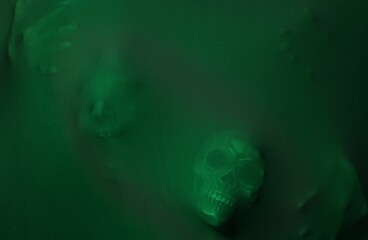 Silhouette of creepy ghost with skulls behind green cloth