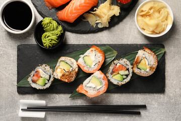 Different tasty sushi rolls on light grey table, flat lay