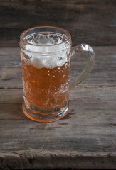 Vintage mug of light beer on a old wooden background; vertical picture