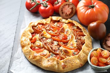Tasty galette with tomato and cheese (Caprese galette) on dark textured table, closeup