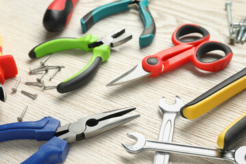 Different pliers, scissors and other tools for repair on wooden table, closeup